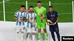 L'Argentin Lionel Messi tient le Ballon d'or, l'Argentin Enzo Fernandez tient le prix du Meilleur jeune joueur, l'Argentin Emiliano Martinez tient le Gant d'or et le Français Kylian Mbappé tient le Soulier d'or, le 18 décembre 2022.