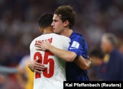 Brenden Aaronson (États-Unis - en bleu) et Abolfazl Jalali (Iran - en blanc) s'embrassent après le match entre leurs deux pays à Doha, le 29 novembre 2022.