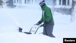 A man clears snow from his driveway following a winter storm that hit the Buffalo region in Amherst, New York, Dec. 25, 2022. 