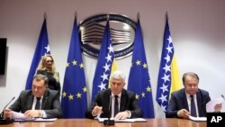 Bosnian Serb leader Milorad Dodik, left, Bosnian Croat leader Dragan Covic, center, and Bosniac leader Nermin Niksic sign a coalition document in Sarajevo, Bosnia, on Dec. 15, 2022.
