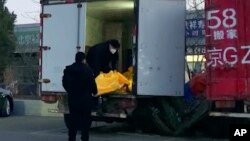 Workers load body bags into a truck at a funeral complex in Beijing, Dec. 16, 2022.