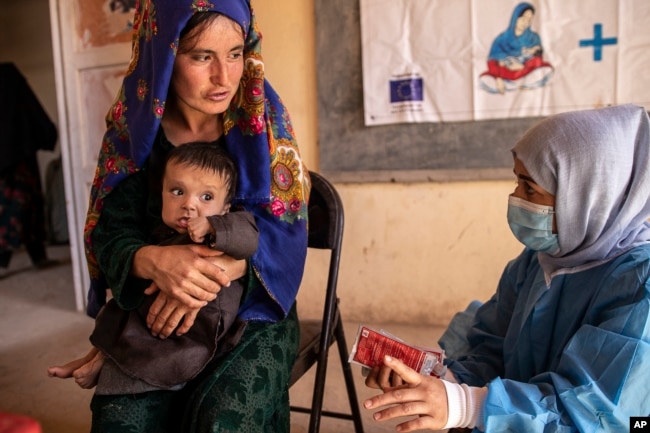 FILE - A Save the Children nutrition counselor, right, explains to Nelab how to feed her 11-month-old daughter, Parsto, with special food, in Sar-e-Pul province of Afghanistan, Thursday, Sept. 29, 2022. (Save the Children via AP, File)