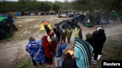 Migranti se pokušavaju zagrijati oko vatre u kampu nedaleko od američke granice, na području Matamorosa u Meksiku, 23. decembra 2022.