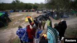 미국과 멕시코 국경지대인 멕시코 마타모로스 임시 야영 시설에서 23일 미국 망명을 원하는 사람들이 불을 쬐고 있다. 