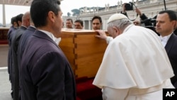 In this image released by the Vatican Media news service, Pope Francis touches the coffin of late Pope Emeritus Benedict XVI after his funeral mass in St. Peter's Square at the Vatican, Jan. 5, 2023.