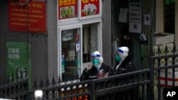 24일 신종 코로나 바이러스 방역을 위해 출입이 통제된 중국 베이징의 주택가에서 방호복을 입은 사람들이 아침을 사먹고 있다.
