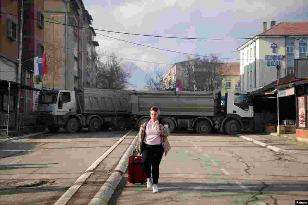 A woman walks near a roadblock, in the northern part part of the ethnically-divided town of Mitrovica, Kosovo.