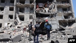FILE - A war crimes prosecutor, center, looks at a destroyed building with workers after the building was hit by a missile strike in the Ukrainian town of Sergiyvka, near Odesa, killing at least 18 people and injuring 30, on July 1, 2022.