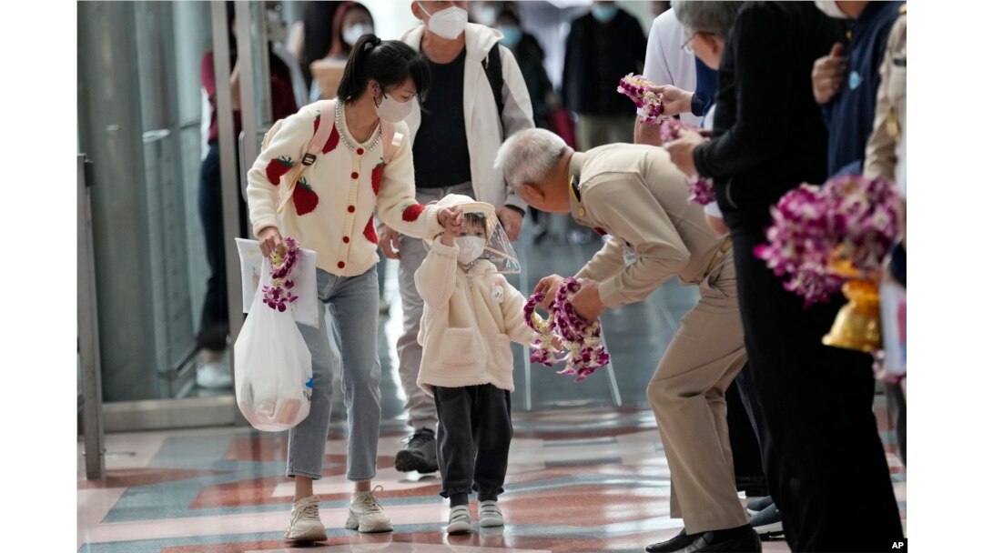 Seorang pejabat Thailand memberikan karangan bunga kepada turis China setibanya di Bandara Internasional Suvarnabhumi, provinsi Samut Prakarn, Thailand, Senin, 9 Januari 2023. (AP/Sakchai Lalit)