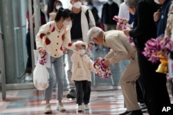 Seorang pejabat Thailand memberikan karangan bunga kepada turis China setibanya di Bandara Internasional Suvarnabhumi, provinsi Samut Prakarn, Thailand, Senin, 9 Januari 2023. (AP/Sakchai Lalit)