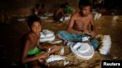 বাংলাদেশের রংপুর জেলার হারাগাছে একটি ছোট "বিড়ি" কারখানায় স্থানীয়ভাবে উৎপাদিত তামাক দিয়ে হাতে করে সিগারেট বানাচ্ছে এক শিশু শ্রমিক। (ফাইল ছবি) 