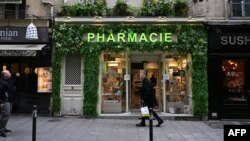FILE - Men walk past a pharmacy in Paris, France, Nov. 24, 2022. As of Jan. 1, 2023, pharmacies in the country will be stocking free condoms for anyone under the age of 25.