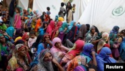 Women displaced because of the floods wait to receive food while taking refuge in a camp in Sehwan, Pakistan, Sept. 30, 2022.