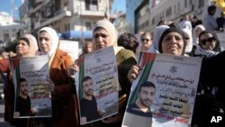 Warga Palestina memegang poster tahanan Palestina Nasser Abu Hamid selama protes, Selasa, 20 Desember 2022, di kota Ramallah, Tepi Barat, setelah dia meninggal karena kanker paru-paru di Israel. (AP/Majdi Mohammed)