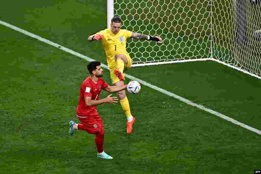 Attauqant ya Iran #09 Mehdu Taremi (G) ameki kotia mongete liboso lya myambi ya Grande-Bretagne #01 Jordan Pickford na match ya groupe B ya Mondial Qatar 2022, na stade Khalifa, Doha, 21 novembre 2022. (Photo Anne-Christine POUJOULAT / AFP)