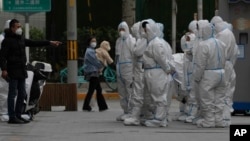 Workers in protective gear gather for their duties in Beijing, Nov. 28, 2022. 