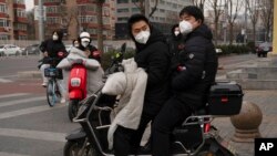 Residents wearing masks cross an intersection in Beijing, Dec. 2, 2022.