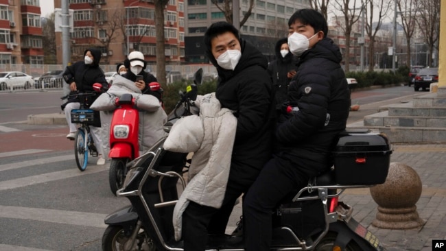 Residents wearing masks cross an intersection in Beijing, Dec. 2, 2022.