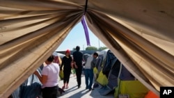 Migrantes caminan junto a sus tiendas de campaña en el refugio Senda de Vida 2 en Reynosa, México, el 15 de diciembre de 2022.