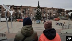 Local citizens walk near a Christmas tree decorated for Orthodox Christmas and the New Year festivities in Mariupol, in Russian-controlled Donetsk region, eastern Ukraine, Jan. 5, 2023.