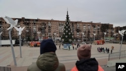 Residentes locales caminan cerca de un árbol de Navidad decorado para las festividades ortodoxas de Navidad y Año Nuevo en Mariupol, en la región de Donetsk controlada por Rusia, en el este de Ucrania, el 5 de enero de 2023.