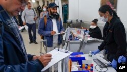 Shubham Chandra, center, returning home to New York from Mexico, takes an anonymous COVID test for study purposes after arriving at Newark Liberty International Airport in Newark, New Jersey, Jan. 4, 2023. 