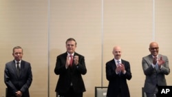 From left, Venezuelan opposition delegate Gerardo Blyde Perez, Mexico Foreign Minter Marcelo Ebrad, Norwegian diplomat Dag Nylander and President of the National Assembly of Venezuela, Jorge Rodriguez, applaud after agreeing to create a U.N.-managed fund to aid Venezuela's poor.