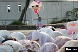 FOTO FILE: Gadis muslimah memegang balon saat mengikuti salat berjamaah Idulfitri di pelabuhan Sunda Kelapa, Jakarta, 2 Mei 2022. (REUTERS/Willy Kurniawan)