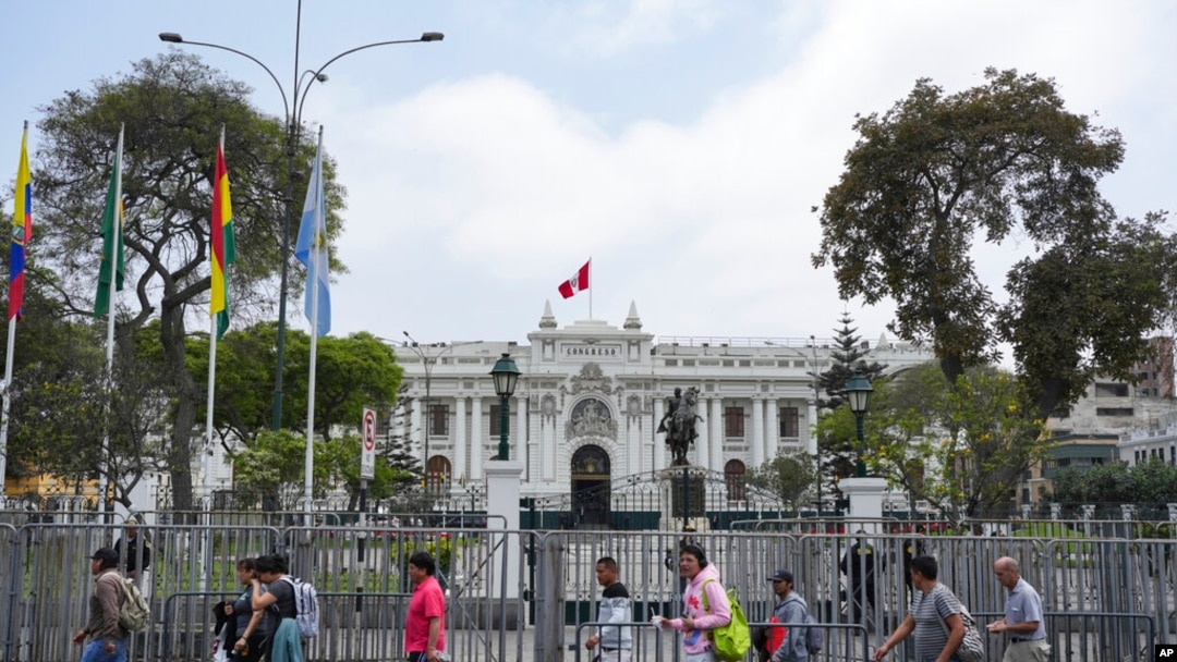ARCHIVO - Personas pasan frente al Congreso durante una visita de una delegación de la OEA en Lima, Perú, el lunes 21 de noviembre de 2022.