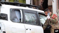A Lebanese army investigator talks on his phone as he checks a damaged U.N. peacekeeper vehicle at the scene where a U.N. peacekeeper convoy came under gunfire in the Al-Aqbiya village, south Lebanon, Dec. 15, 2022. 