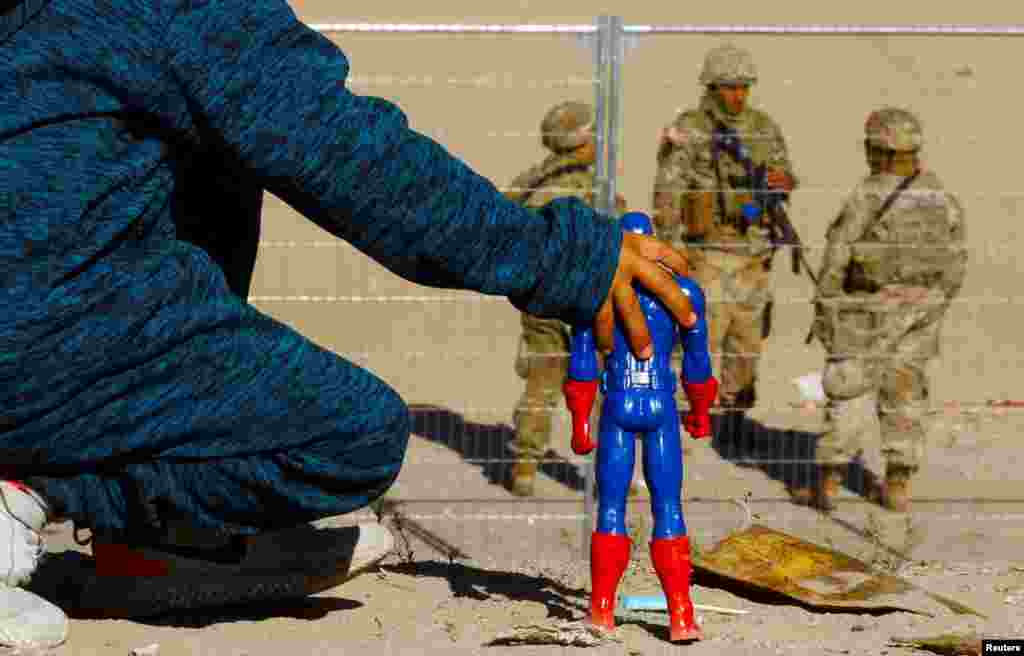 George, 5, a migrant boy from Venezuela, plays with a Captain America doll at the border between Mexico and the United States, as members of the Texas National Guard stand guard on the banks of the Rio Bravo river, seen from Ciudad Juarez, Mexico, Dec. 27, 2022.&nbsp;George is&nbsp;s traveling with his family and trying to seek asylum in the United States.