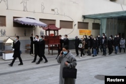 四川成都一个火葬场工作人员抬着一名逝者的骨灰盒走出火葬场。(2022年12月28日)
