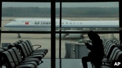 2022年10月29日，中国国际航空一架客机滑行驶过北京首都国际机场时，一名乘客在看手机。（美联社照片）