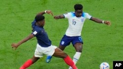 France's Aurelien Tchouameni, left, challenges for the ball with England's Bukayo Saka during the World Cup quarterfinal soccer match between England and France, at the Al Bayt Stadium in Al Khor, Qatar, Dec. 10, 2022. France beat England 2-1.