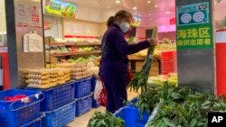 A woman shops in a reopened grocery store in the district of Haizhu as pandemic restrictions are eased in southern China's Guangzhou province, Dec. 1, 2022.