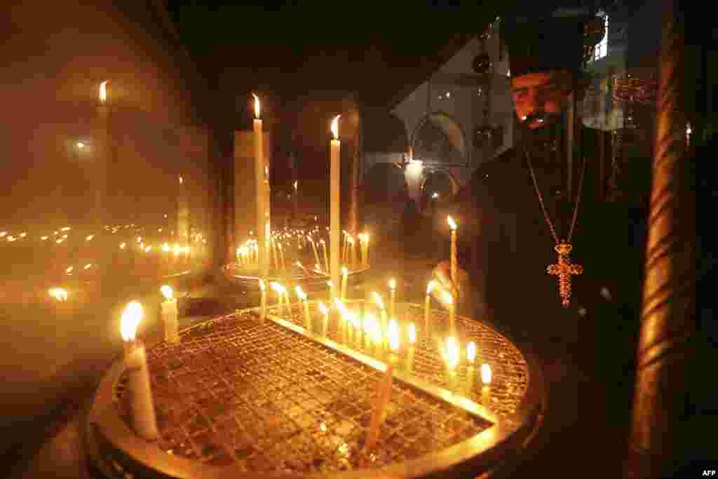 A priest lights a candle at the Nativity Church in the biblical city of Bethlehem, as Christian denominations celebrate Christmas according to the Eastern calendar.