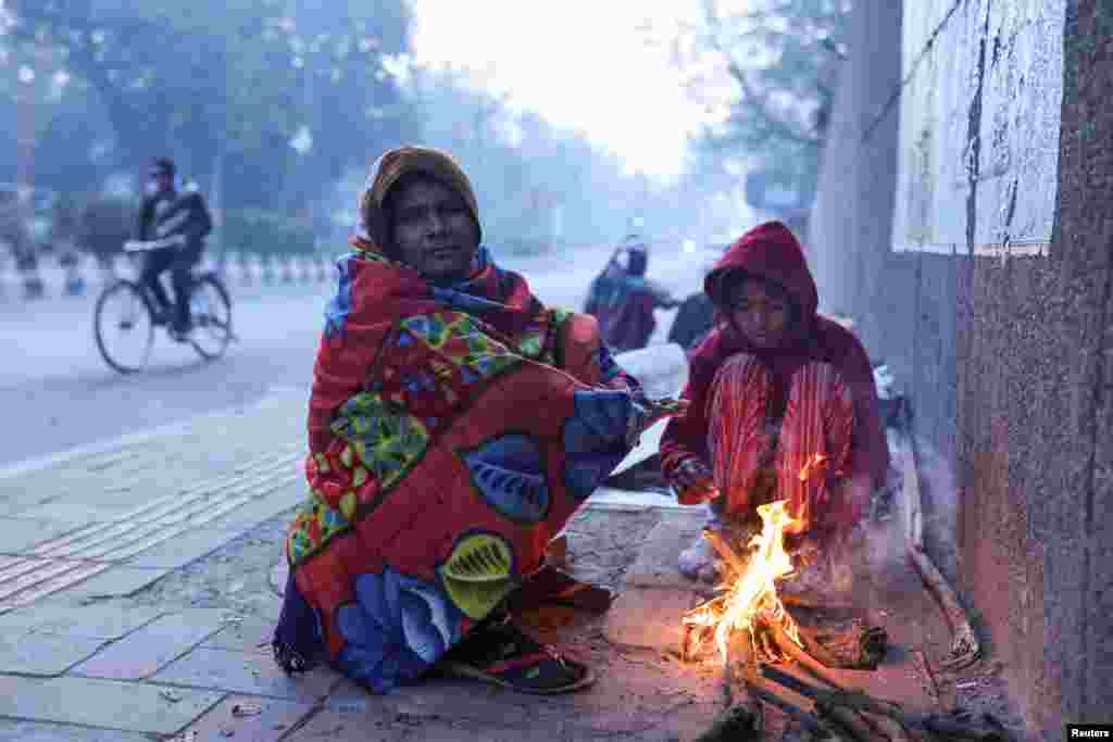 Una mujer y su hija se calientan junto a una hoguera durante en una fría mañana de invierno en Nueva Delhi, India. REUTERS/Anushree Fadnavis.