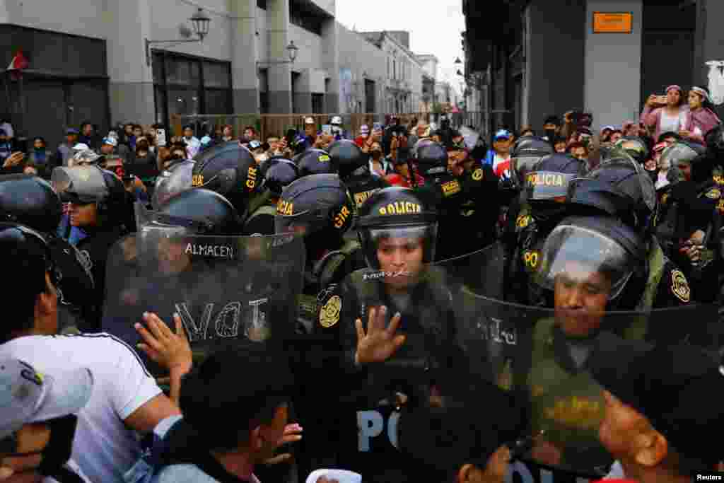 Agentes de policía montan guardia mientras los manifestantes participan en una protesta el 11 de diciembre de 2022 para exigir la disolución del Congreso en Perú y celebrar elecciones democráticas.