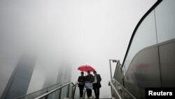 People wearing masks walk on an overpass at Lujiazui financial district in Shanghai, China, Dec. 9, 2022.
