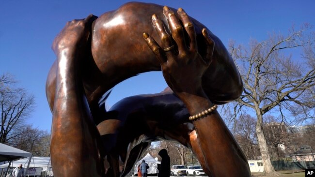 Un transeúnte camina bajo la escultura de bronce de 20 pies de altura "El Abrazo", un monumento al Dr. Martin Luther King Jr. y Coretta Scott King, en el Boston Common, el 10 de enero de 2023, en Boston, EEUU,