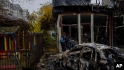 Residents check the damage of a shop destroyed a day earlier during a Russian attack in Kherson, southern Ukraine, Nov. 25, 2022. 