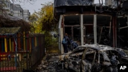 FILE - Residents check the damage of a shop destroyed a day earlier during a Russian attack in Kherson, southern Ukraine, Nov. 25, 2022.