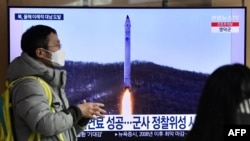 A man at a Seoul railway station walks past a television showing file footage of a North Korean missile test, Dec. 31, 2022 .