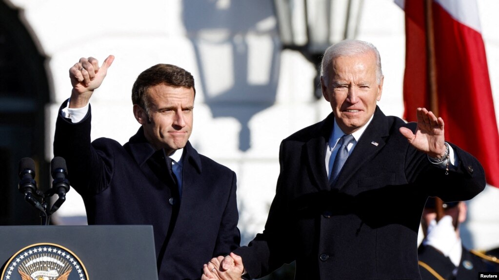 2022年12月1日，法国总统马克龙（Emmanuel Macron）和美国总统拜登在白宫南草坪上举行的国家元首到访正式欢迎仪式上手握手站在一起。拜登总统和马克龙总统在当天的闭门会谈中讨论的如何寻求结束俄乌冲突等问题.(photo:VOA)