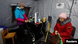 Local residents charge their devices, use internet connection and warm up inside an invincibility centre after critical civil infrastructure was hit by Russian missile attacks in Kyiv, Nov. 24, 2022. 