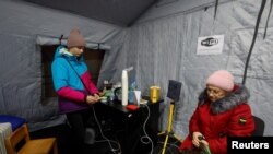 Local residents charge their devices, use internet connection and warm up inside an invincibility centre after critical civil infrastructure was hit by Russian missile attacks in Kyiv, Nov. 24, 2022. 