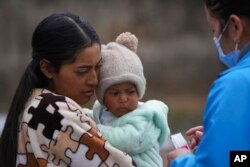 Marina, who did not want to give her last name, is given vitamins for her child from a Health Ministry worker who is going house to house in the Cotopaxi province of Ecuador, Dec. 2, 2022.