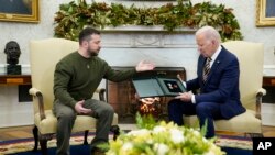 FILE: Ukrainian President Volodymyr Zelenskyy speaks after giving President Joe Biden a gift as they meet in the Oval Office of the White House, Wednesday, Dec. 21, 2022, in Washington.