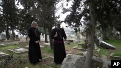 Hosam Naoum, uskup Anglikan Palestina (kanan), bersama seorang rekannya meninjau Pemakaman Protestan bersejarah di Gunung Zion Yerusalem di Yerusalem, yang dirusak pengacau, Rabu, 4 Januari 2023. (AP/ Mahmoud Illean)