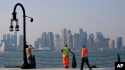 Dengan latar belakang cakrawala kota, para pekerja migran beristirahat di pelabuhan Doha, di Doha, Qatar, Minggu, 13 November 2022. (Foto: AP)